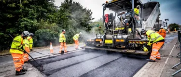 Aggregate Industries workers resurfacing a road with tools and machinery.