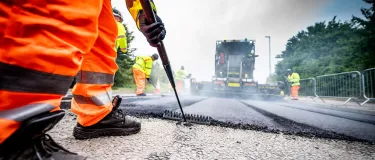 An Aggregate Industries worker uses a rake while resurfacing a road.