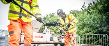 Worker shovels fresh asphalt onto new road