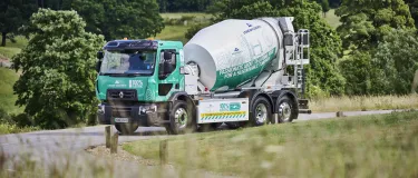 Aggregate Industries' new electric concrete mixer driving through woodland. It will be the first e-mixer to operate in London.