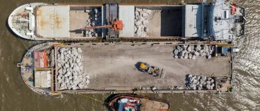 Armourstone granite bolders being transfered from a ship to a sea barge on its way from Glensanda to Blue Anchor Beach in Somerset
