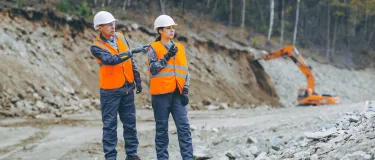 Man and woman in quarry wearing high viz vests and hard hats