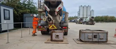 A driver in PPE stand alongside a mixer truck at Whetstone Readymix taking part in the trials of recycled concrete fines.