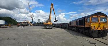 A freight rail train delivering materials from Bardon Hill Quarry to Sunderland. In the background is an excavator ready to unload the wagons.
