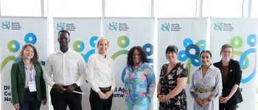 Seven individuals lined up in front of EDI themed roller banners