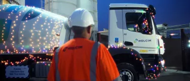Mixer truck with christmas lights around it at night with a man in PPE in the foreground
