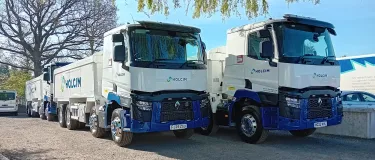 several asphalt trucks under a tree with the Holcim logo
