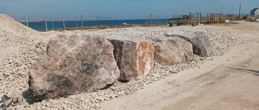 Limestone rock armour boulder from Holcim's Torr Quarry being put into new sea defences at Newtons Cove in Weymouth