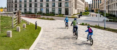 Three cyclists riding along a paved path in a modern housing area