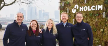 People standing in front of a living wall sign for Holcim in London