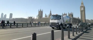 A Holcim UK mixer truck crossing Westminster Bridge in front of the House of Parliament in London