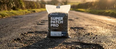 road with potholes during golden hour with a bag called Super Patch Pro in the middle