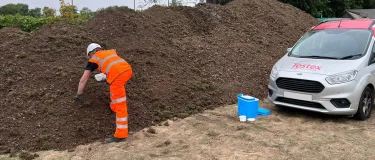 PPE worker inspecting soil next to a Testex car