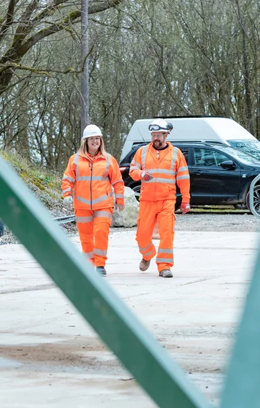 Emily Freeman in high viz PPE walking alongside a male colleague also in high viz PPEat Holcim Mortars at Holme Park