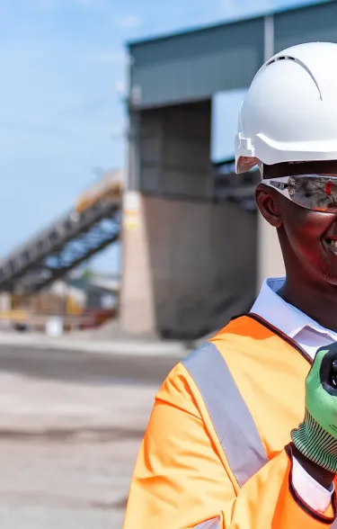 Man wearing PPE holding a radio in an industrial manufacturing area
