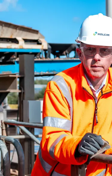 Man wearing PPE leaning against a railing in an industrial setting