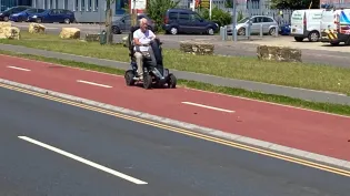 man on mobility scooter on red cycle path