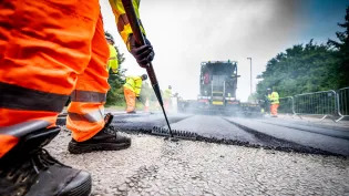 An Aggregate Industries worker uses a rake while resurfacing a road.