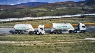 Two cement tankers with the Ecoplanet green cement logo on the side driving through the countryside