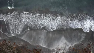 Drone image looking directly downward onto a beach with waves rolling in