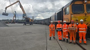 Holcim representatives with partners involved in new rail route from Bardon to Sunderland in high viz PPE in front of a freight train.