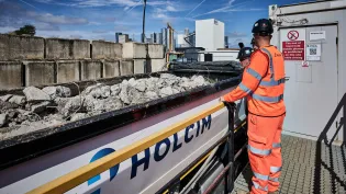 Holcim truck with CDM in the back with a PPE dressed worker inspecting