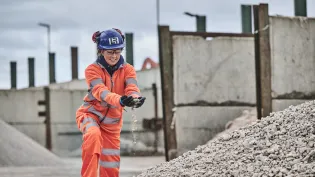 A female worker in high visibility PPE handles construction demolition materials at Holcim Land Recovery's Bordesley Green Recycling Centre
