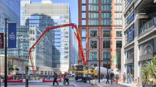 A truck with an extended arm pumping biochar coffee concrete to support the Whale on the Wharf scultpure in Canary Wharf.