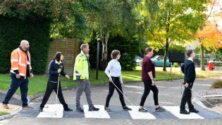 Pupils and staff at New College Worcester walking over a crossing at the school. Materials were donated by Aggregate Industries to carry out improvement works to the grounds.