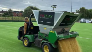 A machine spresding specialist sports sand on a new synthetic pitch at Oasis Academy in Croydon