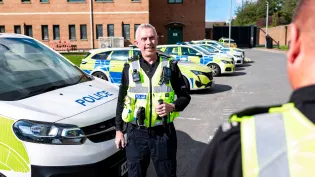 Rob Walsh, CDM North Director in Holcim UK's Aggregate business, also volunteers as a special sergeant with Derbyshire police. The image shpws him in his police uniform at St Mary's Wharf police station in front of police vehicles.