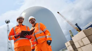 Two works wearing PPE holding a tablet at Holcim Tilbury Cement Terminal