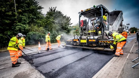 Aggregate Industries workers resurfacing a road with tools and machinery.