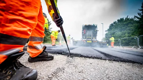 An Aggregate Industries worker uses a rake while resurfacing a road.