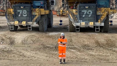 Dump truck driver Elinore Smith at Glensanda Quarry in front of two 100-tonne rigid dump trucks.