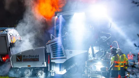 Workers paving the A444 with asphalt pouring into the paver. Dramatic steam and dust.
