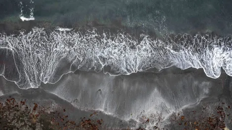 Drone image looking directly downward onto a beach with waves rolling in