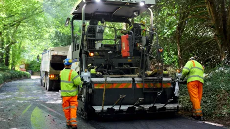 Workers spreading asphalt onto a forest road