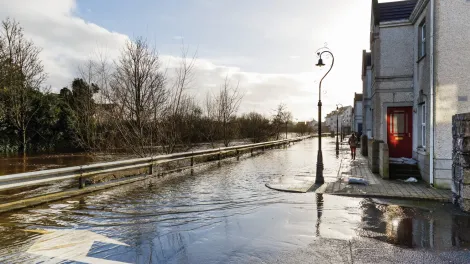 Road submerged by floodwater with a person walking along the path