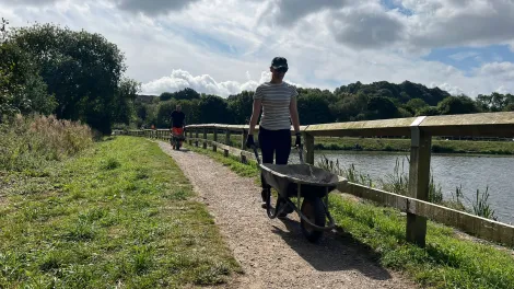 A volunteer from Aggregate Industries pushes a wheelbarrow as part of activity taking place at Codnor Park Reservoir in Derbyshire