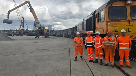 Holcim representatives with partners involved in new rail route from Bardon to Sunderland in high viz PPE in front of a freight train.