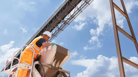 A worker in high visibility clothing checks a mixer truck