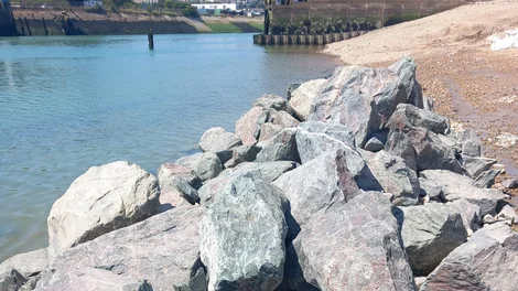 Large angular rocks deployed for coastal protection and riverbank reinforcement at Newhaven Beach.