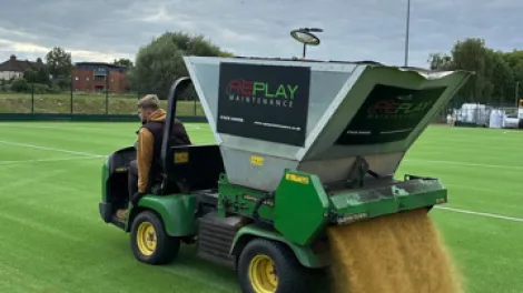 A machine spresding specialist sports sand on a new synthetic pitch at Oasis Academy in Croydon