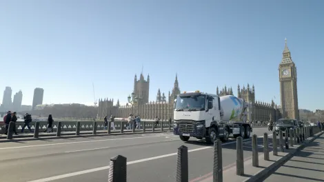 A Holcim UK mixer truck crossing Westminster Bridge in front of the House of Parliament in London