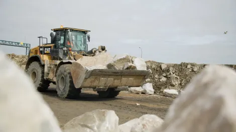 A mechanical loading shovel carries granite boulders delivered from Glensanda Super Quarry to bolster Stallingborough's coastal sea defences