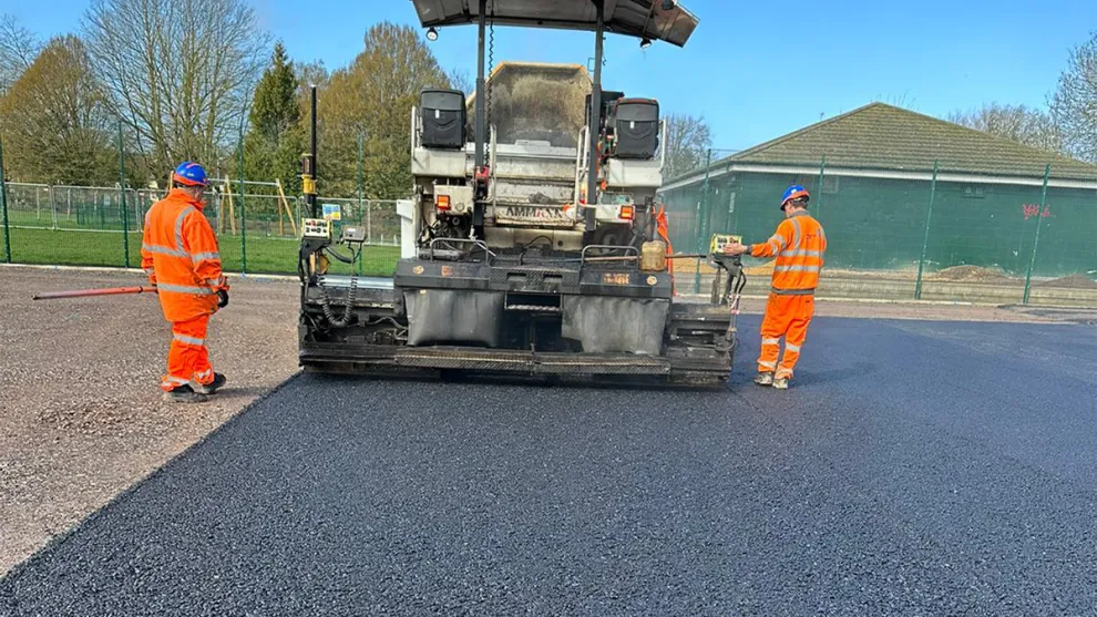 Workers laying the SuperSport Tennis Court at Wolf Fields in Southall
