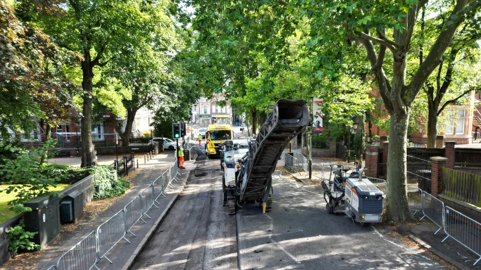 road surrounded by trees in the centre of leicester that's having it's asphalt dug up