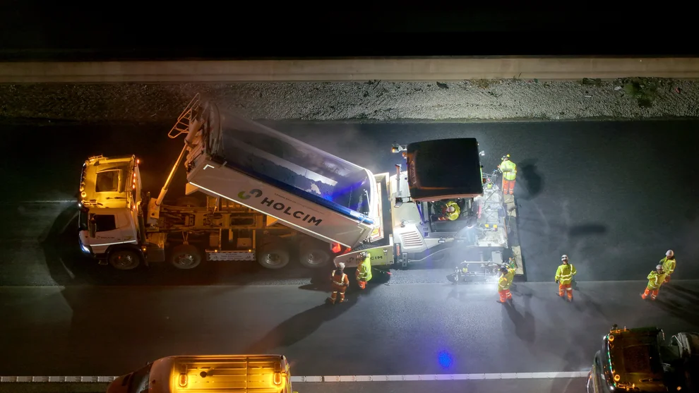 An aerial view of a Holcim truck tipping asphalt on the M5 motorway.