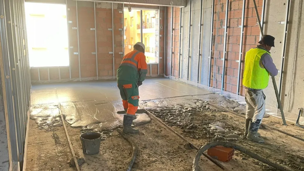 Two workers laying screen in a newly built room